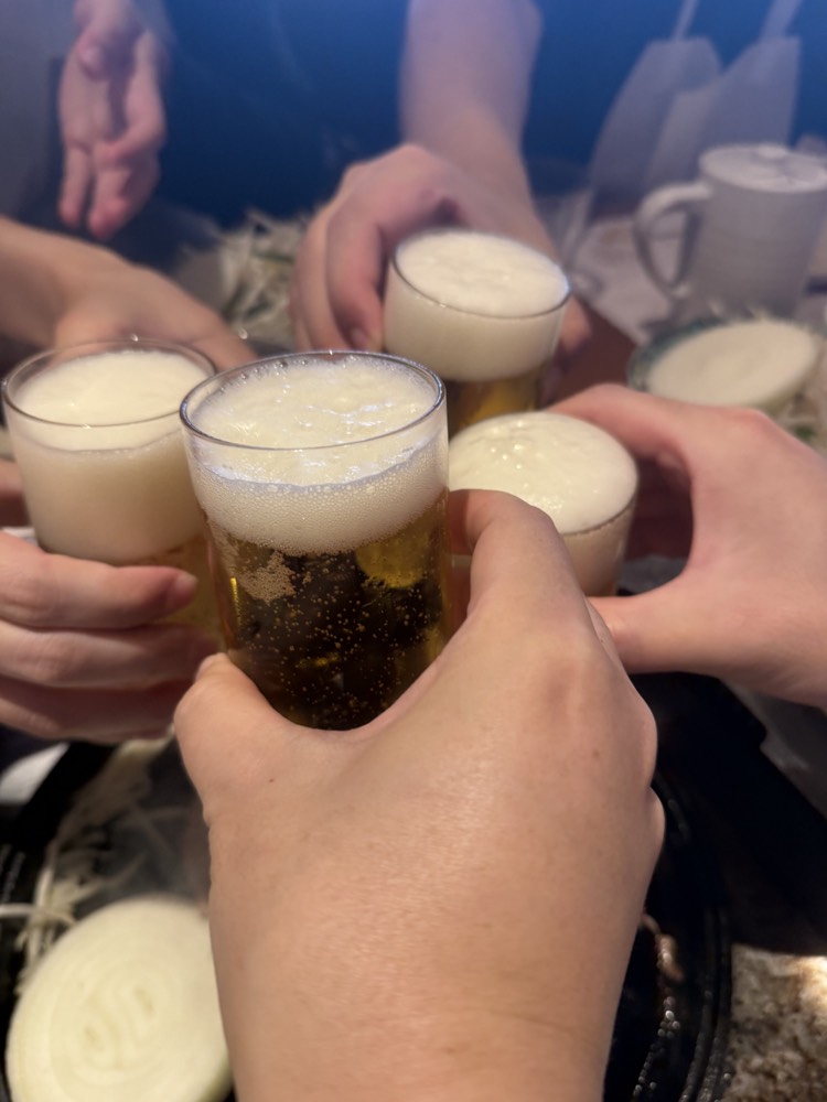 下山後にビールのグラスを寄せて乾杯する手元